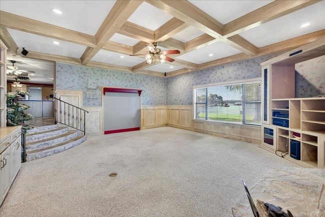 Unfurnished living room featuring ceiling fan, carpet, beam ceiling, coffered ceiling, and wallpapered walls | Image 16