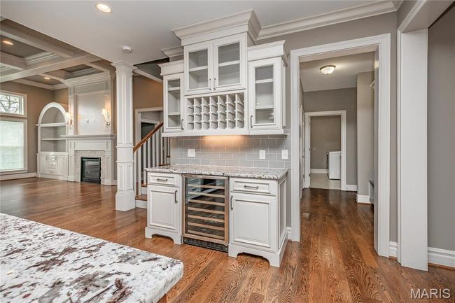Bar featuring ornamental molding, decorative columns, a bar, and beverage cooler | Image 12