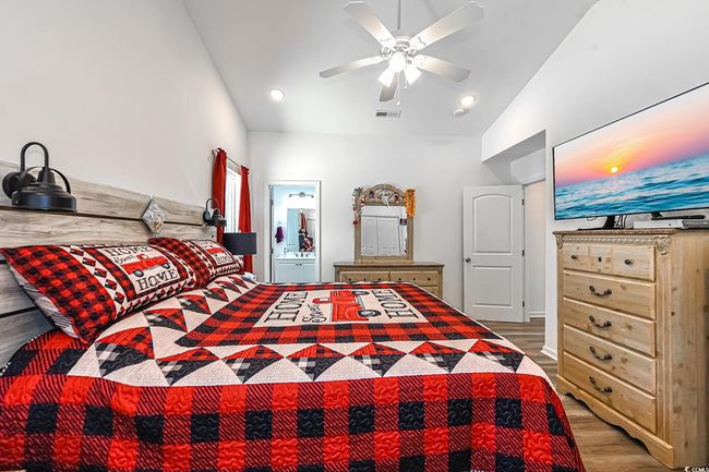 Bedroom featuring wood finished floors, ceiling fan, ensuite bath, and high vaulted ceiling | Image 19