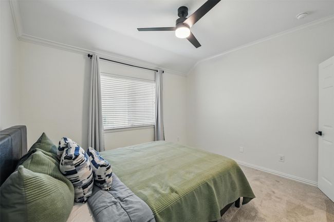 Bedroom with crown molding, light carpet, and a ceiling fan | Image 23