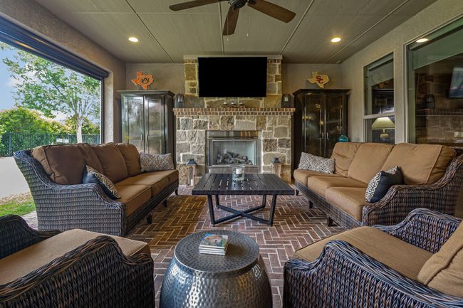Living area featuring a ceiling fan, brick flooring, recessed lighting, and a stone fireplace | Image 30