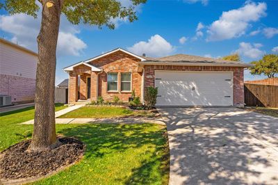 Ranch-style home with central AC, a front yard, and a garage | Image 1