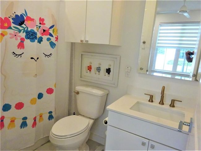 Bathroom with vanity, toilet, and curtained shower | Image 5