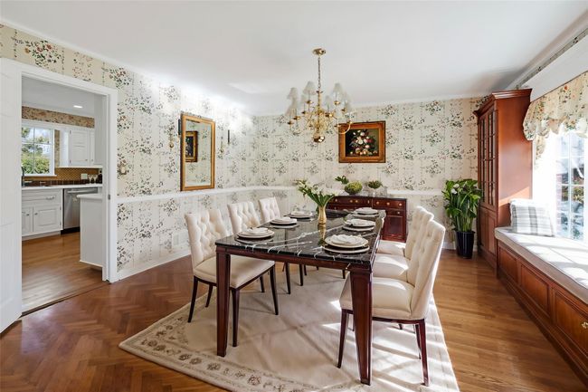 Dining room with parquet floors, wallpapered walls, and a notable chandelier | Image 12