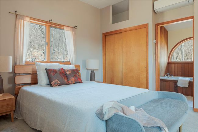 Carpeted bedroom with a closet, a wall mounted AC, and multiple windows | Image 25