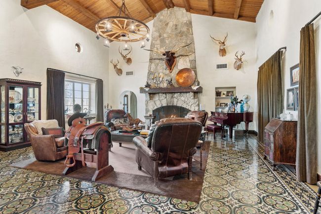 Living area with wood ceiling, high vaulted ceiling, a stone fireplace, and beam ceiling | Image 13