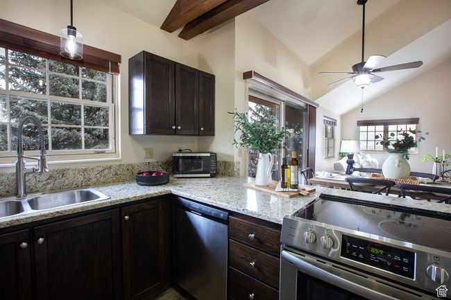 Kitchen featuring stainless steel appliances, a sink, a ceiling fan, dark brown cabinetry, and open floor plan | Image 7