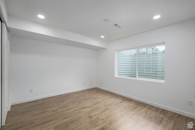 Basement bedoom with wood finished floors, baseboards, visible vents, and recessed lighting | Image 22