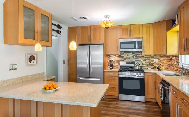 Kitchen with quartz counter surfaces and 3-seater peninsula | Image 8