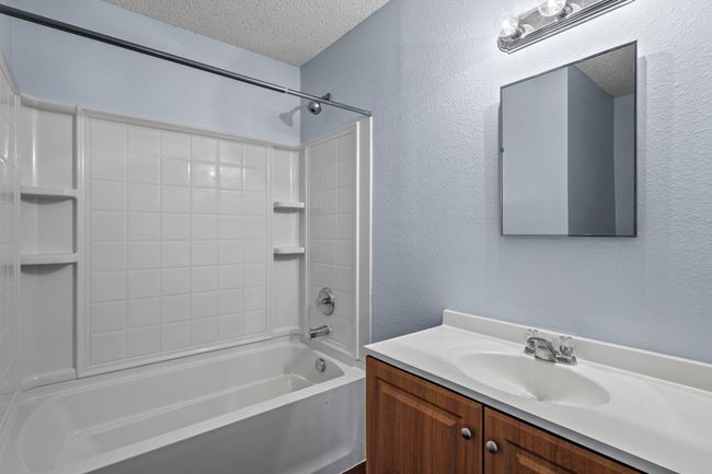 Bathroom with vanity, a textured ceiling, and washtub / shower combination | Image 16