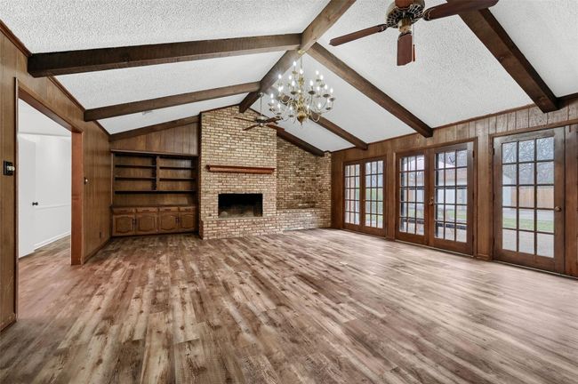 Unfurnished living room featuring a textured ceiling, ceiling fan, wood finished floors, plenty of natural light, and a fireplace | Image 5