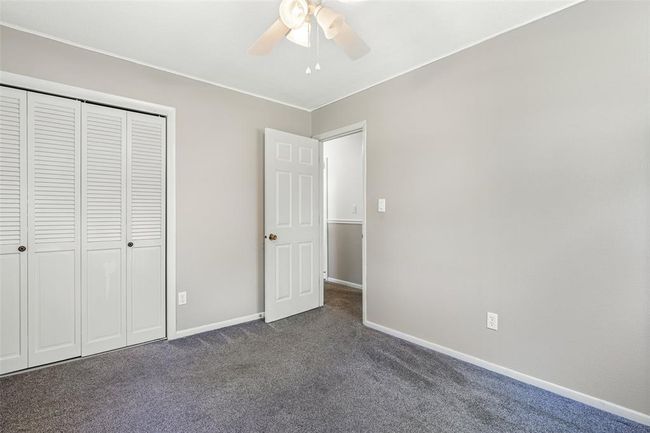 Unfurnished bedroom with dark colored carpet, baseboards, a closet, and a ceiling fan | Image 51