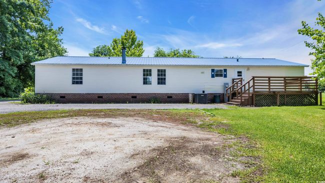 Back of property featuring crawl space, a deck, a metal roof, and a lawn | Image 21