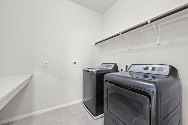 Laundry room with independent washer and dryer and light tile patterned flooring | Image 29
