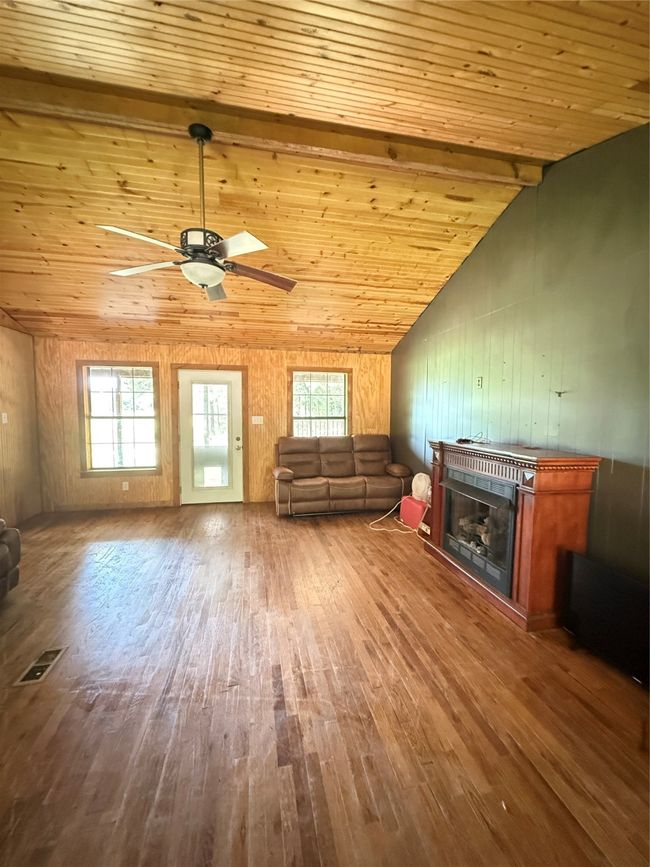Living room with wood finished floors, healthy amount of natural light, a ceiling fan, a glass covered fireplace, and wooden ceiling | Image 17