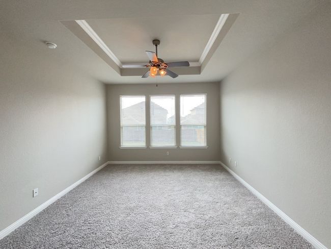 Master bed room featuring a tray ceiling, a ceiling fan, ornamental molding, and a smoke detector | Image 12