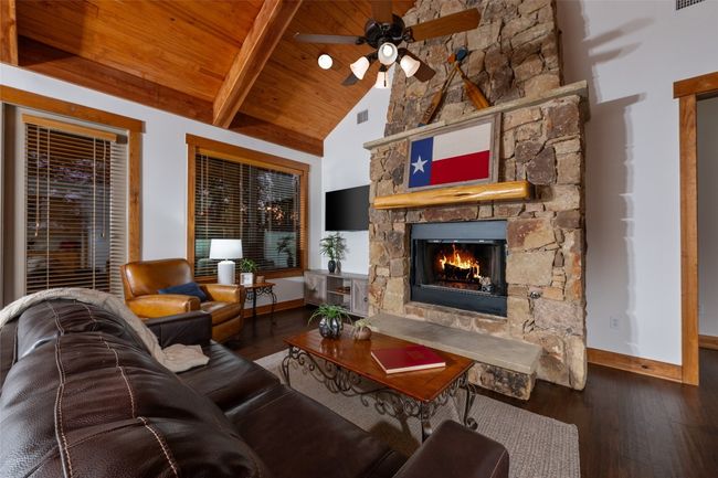 From a different angle, the living room’s vaulted ceiling and exposed beams showcase the craftsmanship, while the stone fireplace is the perfect place to enjoy a cozy fire. | Image 9