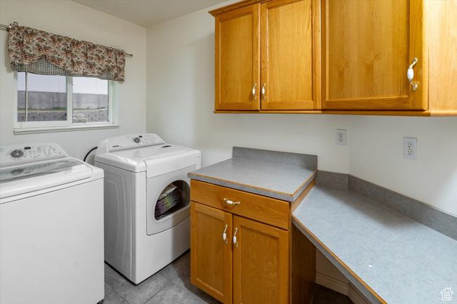 Laundry room featuring washing machine and clothes dryer, cabinets, and light tile patterned floors | Image 30