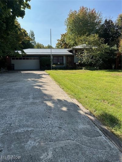 View of front facade with a garage and a front lawn | Image 1