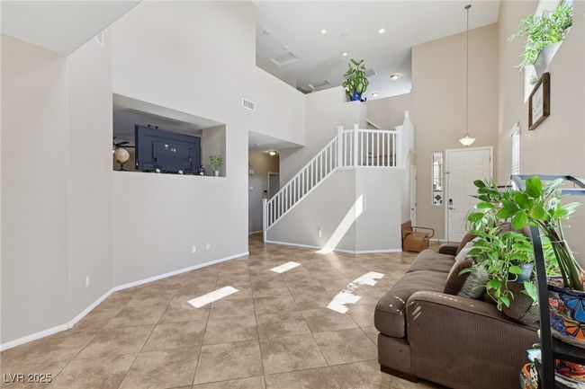 Tiled living room featuring a towering ceiling, stairs, and baseboards | Image 12