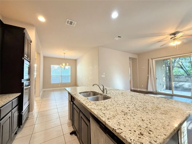 Kitchen featuring a chandelier, ceiling fan, appliances with stainless steel finishes, light stone counters, and recessed lighting | Image 18