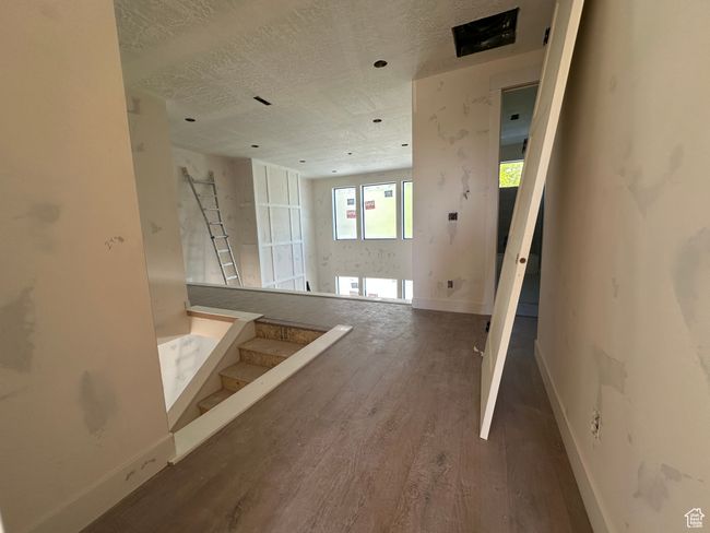 Unfurnished living room with wood finished floors, baseboards, a textured ceiling, and stairway | Image 18