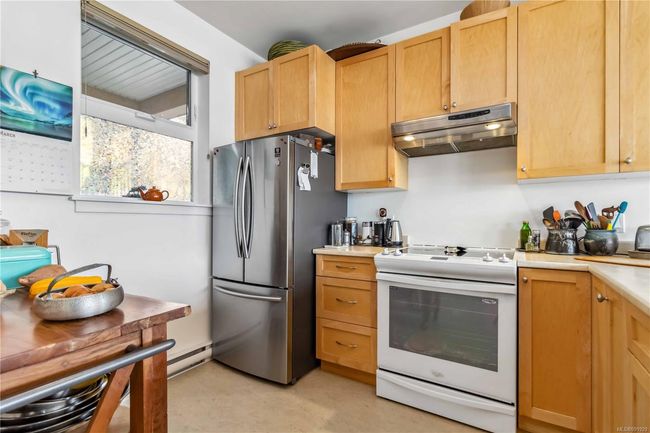 Kitchen with white electric stove, baseboard heating, light countertops, freestanding refrigerator, and under cabinet range hood | Image 11