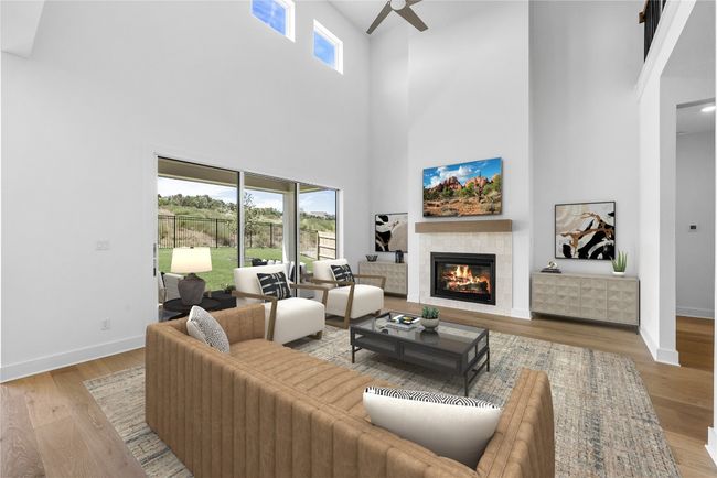 Living area featuring a high ceiling, ceiling fan, a fireplace, and wood finished floors | Image 7