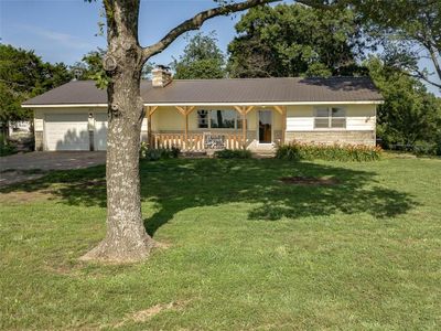 Single story home with a porch, a garage, and a front lawn | Image 1