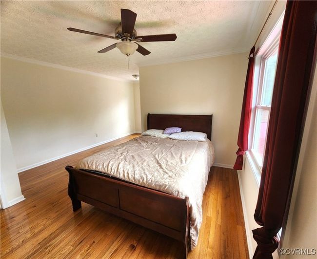 Bedroom with a textured ceiling, wood finished floors, ornamental molding, and ceiling fan | Image 19