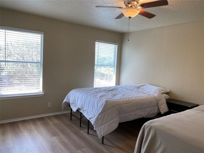 Bedroom featuring wood finished floors, a textured ceiling, baseboards, and a ceiling fan | Image 12