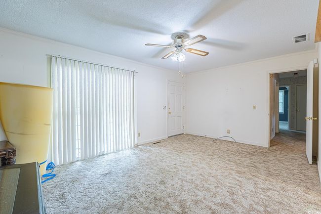 Carpeted spare room with crown molding, a textured ceiling, and ceiling fan | Image 5