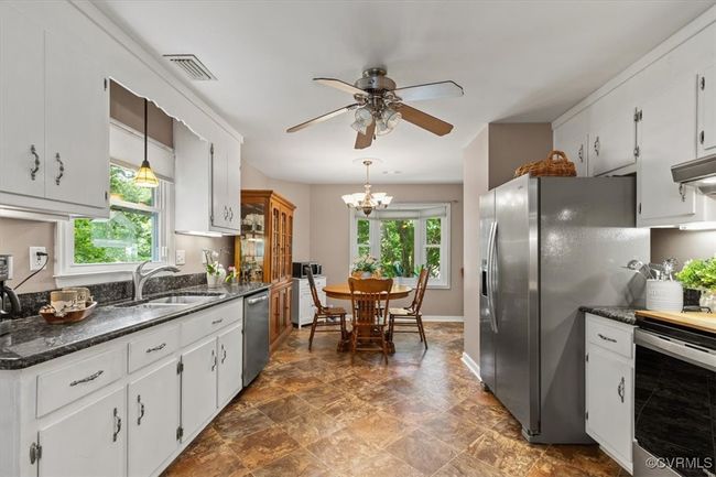 Kitchen with a sink, stainless steel appliances, a ceiling fan, a chandelier, and white cabinetry | Image 13