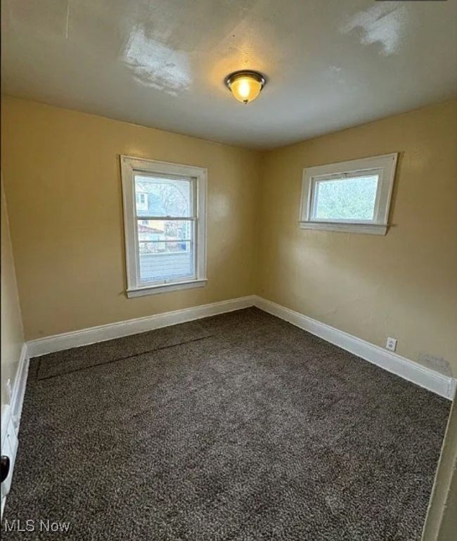 Unfurnished room featuring dark carpet and baseboards | Image 9