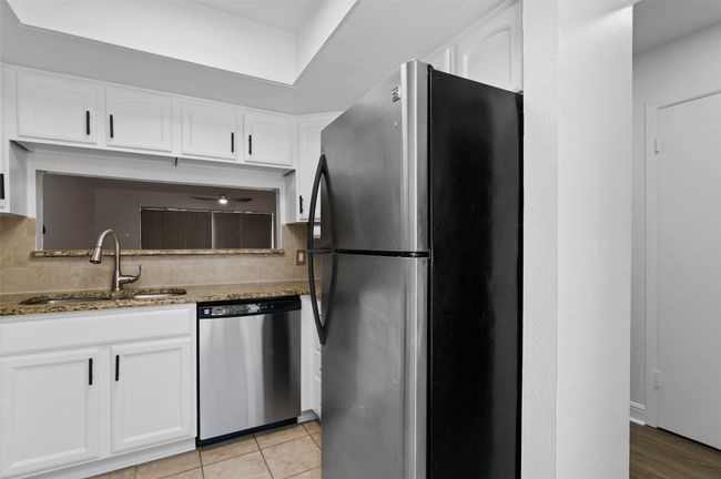 Kitchen with stainless steel appliances, granite counters, white cabinetry, and decorative backsplash | Image 4