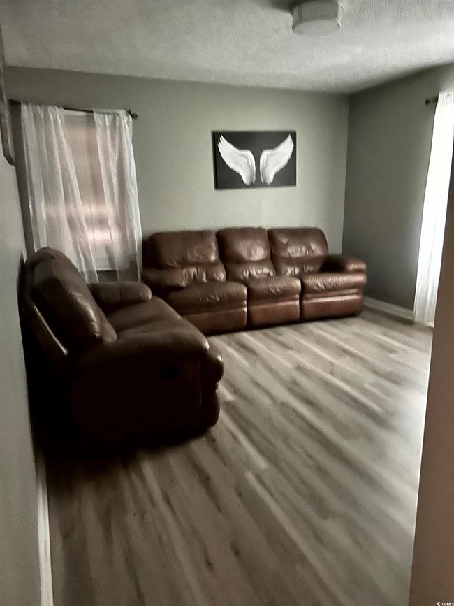 Living area with wood finished floors, a textured ceiling, and baseboards | Image 17