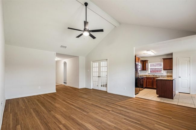 Unfurnished living room with a ceiling fan, high vaulted ceiling, french doors, light wood-style floors, and beam ceiling | Image 5