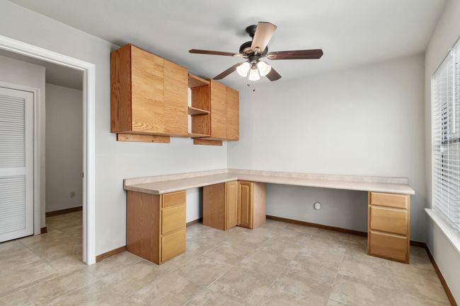 Unfurnished office with built in desk, ceiling fan, and baseboards | Image 33