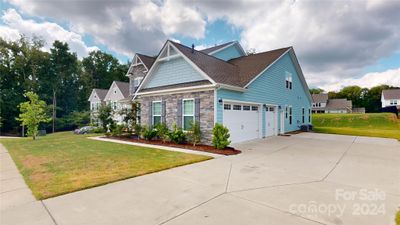 3 car side load garage with service door and extra concrete pad | Image 2