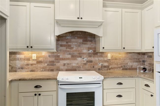 Notice the gorgeous brick backsplash and under-cabinet lighting, which add depth and character to the kitchen. | Image 11