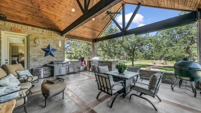 View of patio featuring an outdoor kitchen, outdoor dining area, and view of scattered trees | Image 36