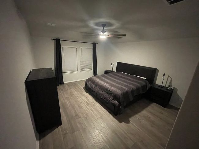 Bedroom with a ceiling fan and wood finished floors | Image 5
