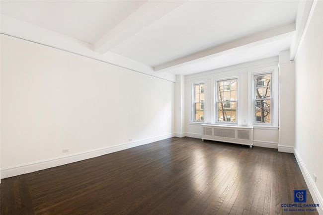 Unfurnished room featuring radiator heating unit, baseboards, beam ceiling, and dark wood finished floors | Image 5