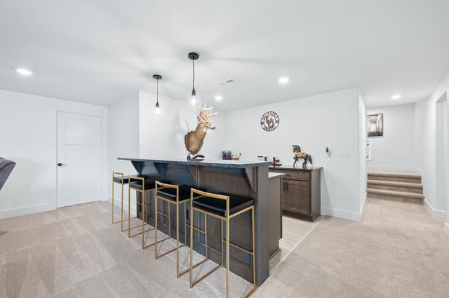 Indoor wet bar with light colored carpet, stairway, baseboards, recessed lighting, and pendant lighting | Image 24