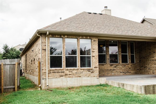Back of property featuring brick siding, a chimney, and roof with shingles | Image 36