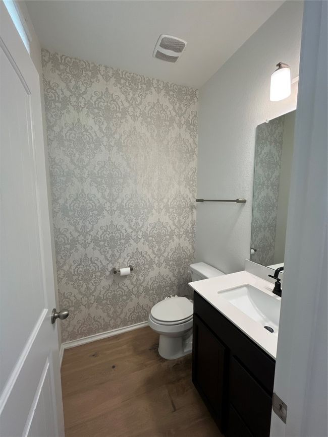 Bathroom featuring visible vents, vanity, wood finished floors, toilet, and wallpapered walls | Image 6