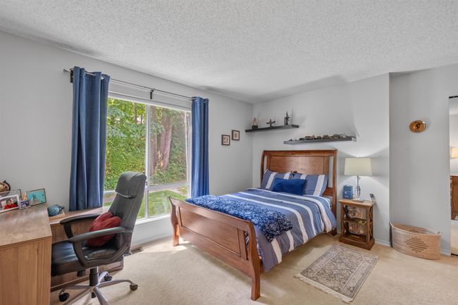 Carpeted bedroom featuring a textured ceiling and an office area | Image 10