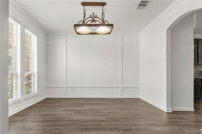 Unfurnished dining area with arched walkways, a decorative wall, ornamental molding, and wood finished floors | Image 4