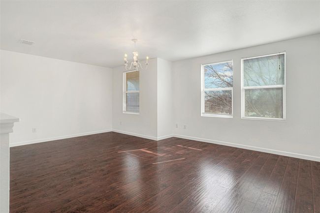 Empty room with a chandelier, baseboards, and dark wood-type flooring | Image 21
