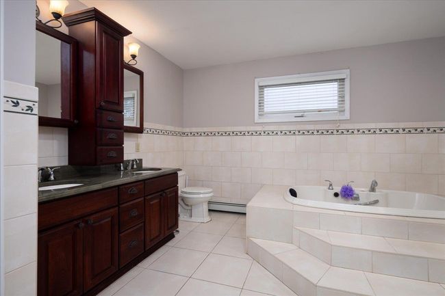 Full bathroom with a baseboard radiator, a garden tub, double vanity, tile patterned floors, and tile walls | Image 22
